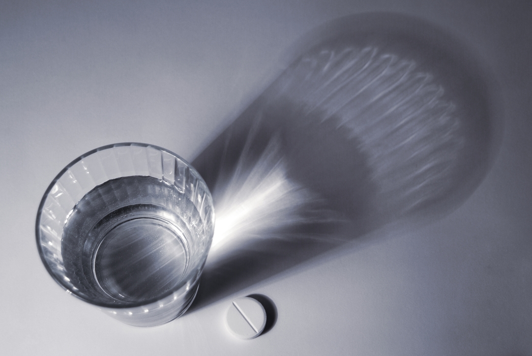 Glass of Water and a Pill with Dramatic Shadow