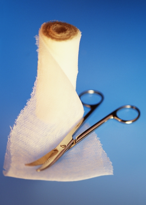 Roll of Gauze Slightly Unrolled with Medical Scissors on Top