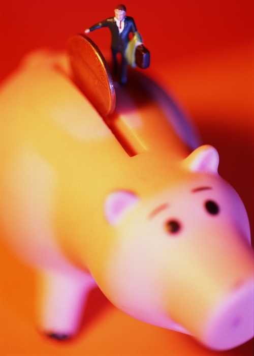 Toy Person Dropping Coin in a Piggy Bank