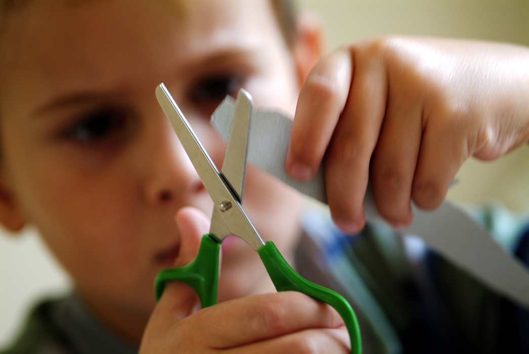 Young Boy Cutting Paper with Scissors